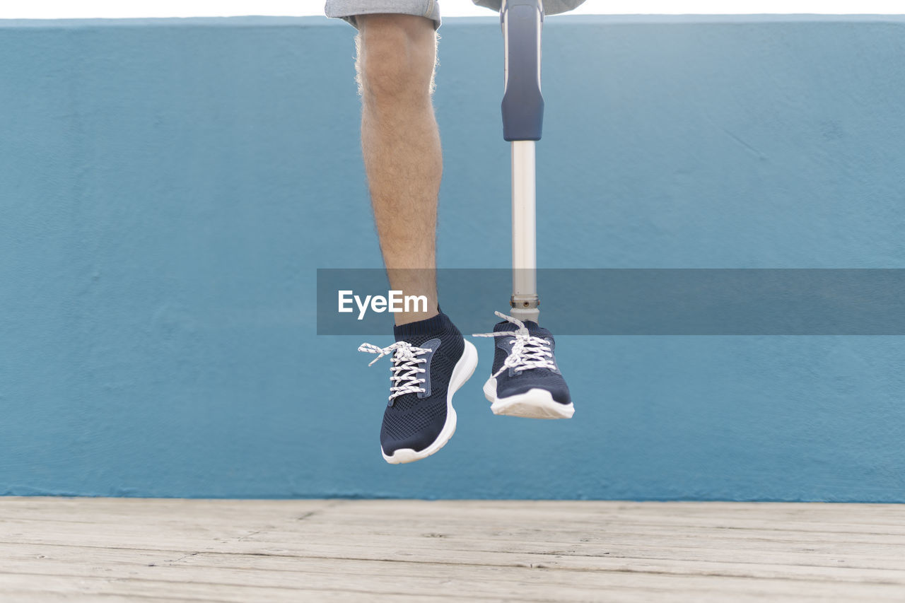 Disabled man jumping against blue wall