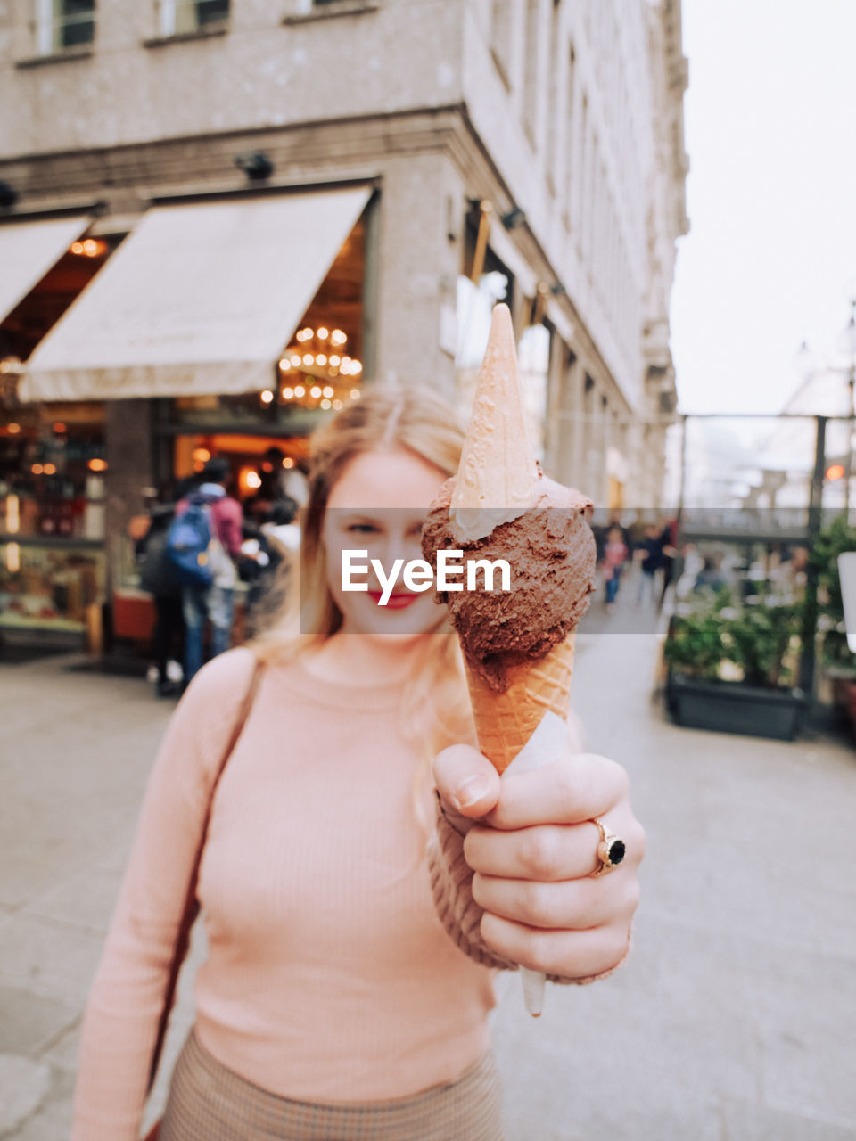 Portrait of woman holding ice cream on footpath