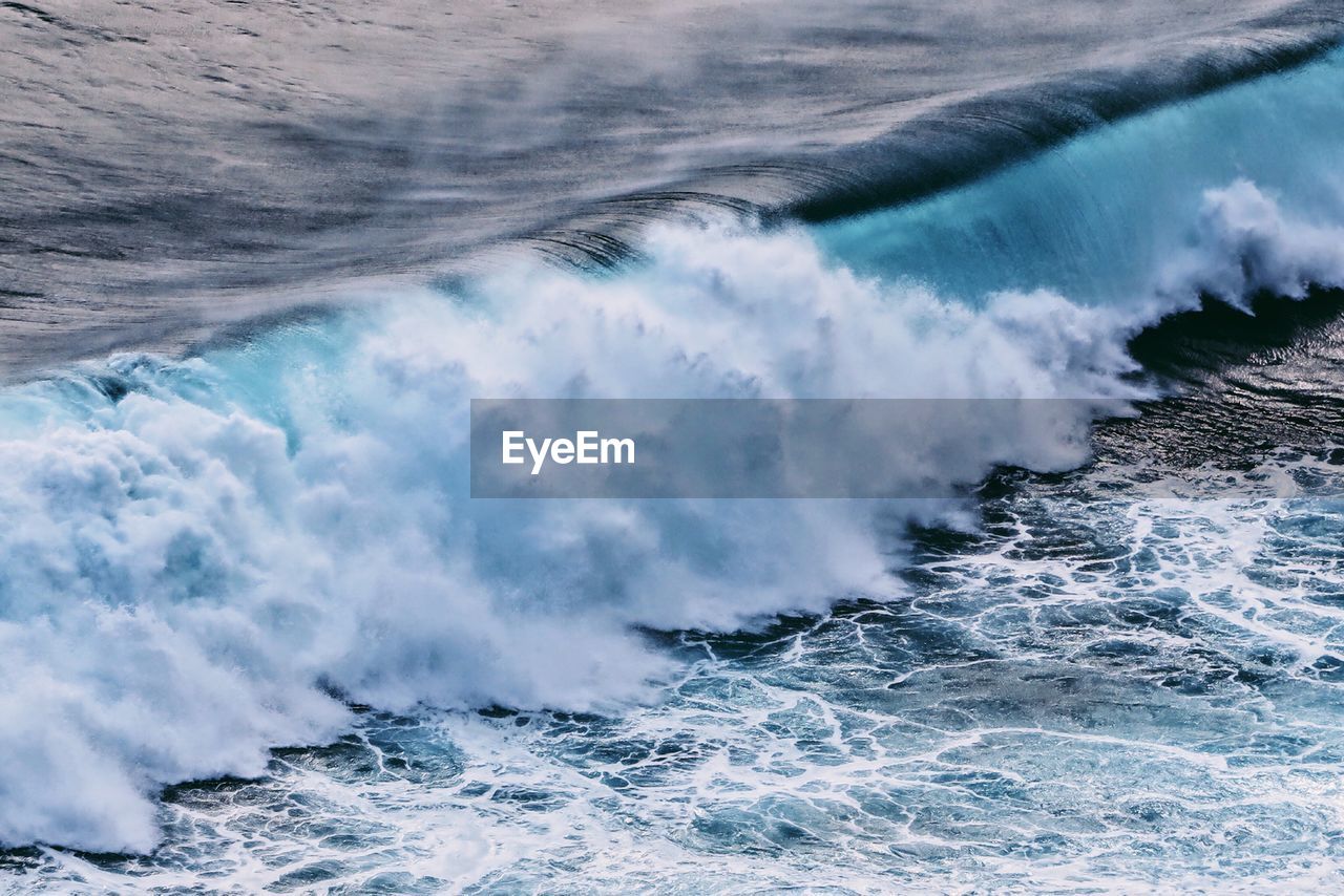 Waves splashing on sea against sky