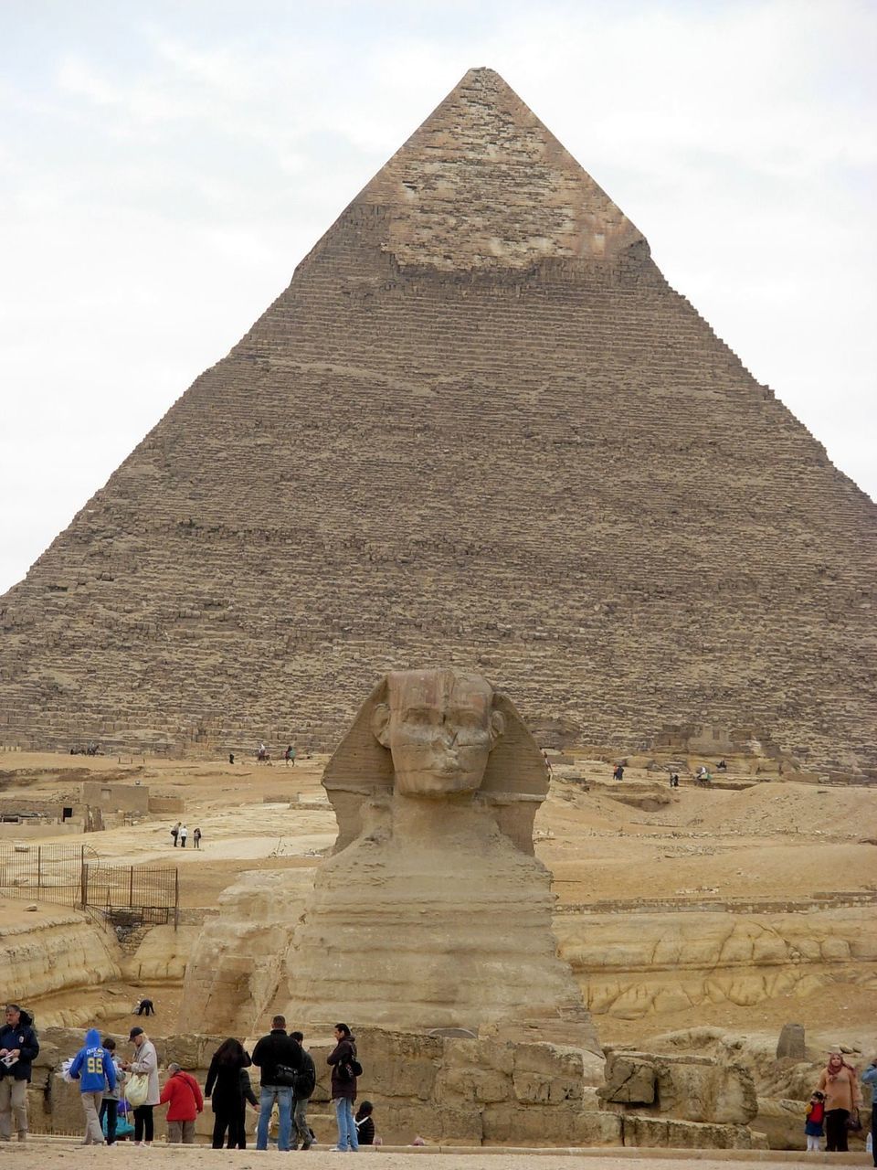 Tourist visiting the sphinx by pyramid against sky