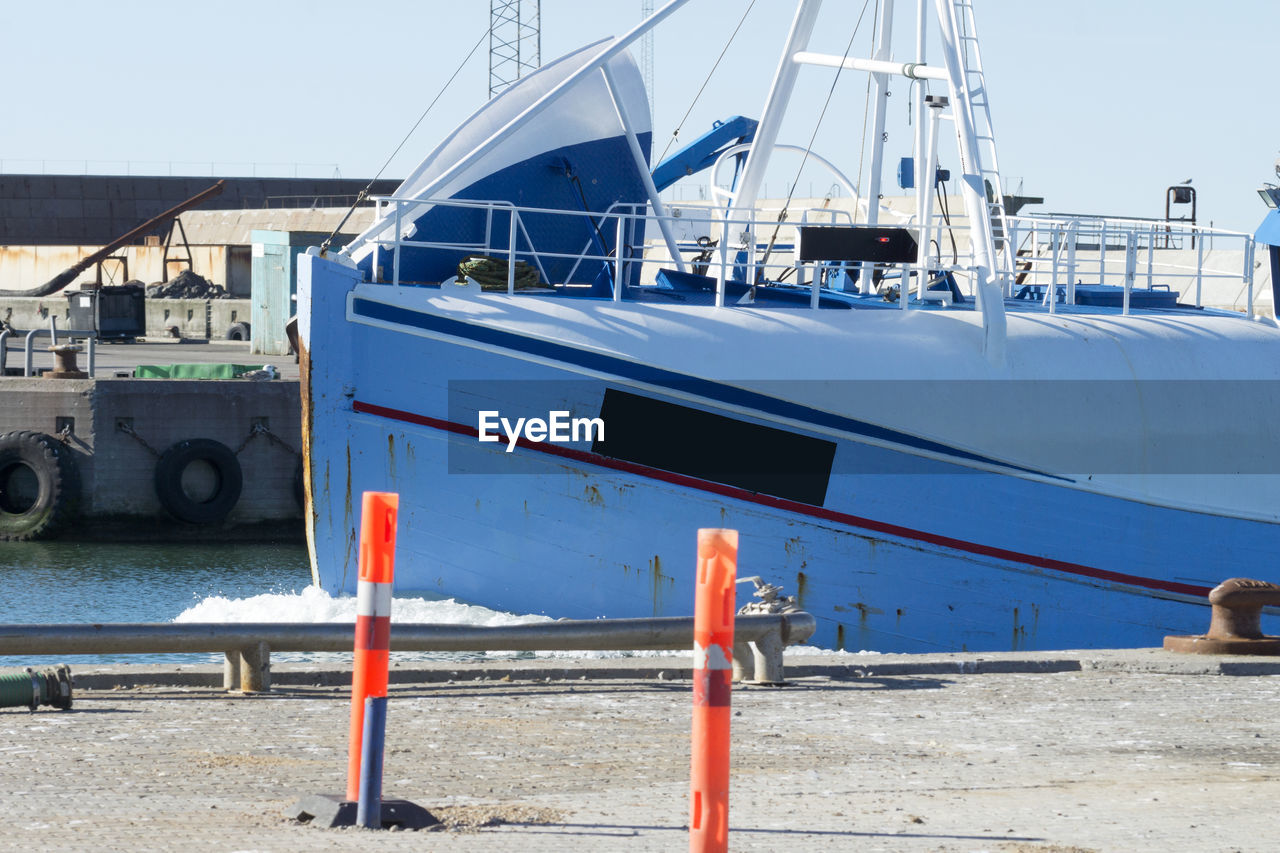 Ship moored at harbor against blue sky