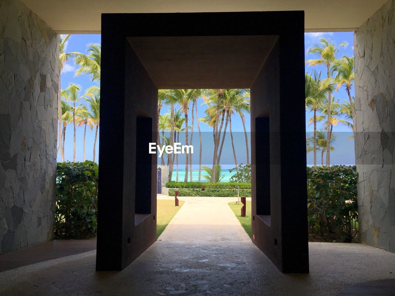 Walkway leading towards palm trees at beach