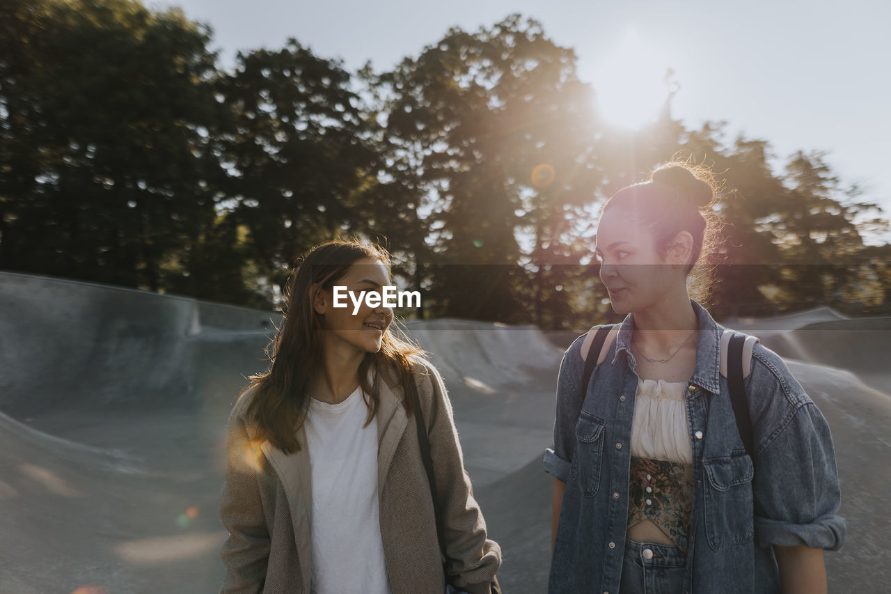 Smiling teenage girls talking together at skate park