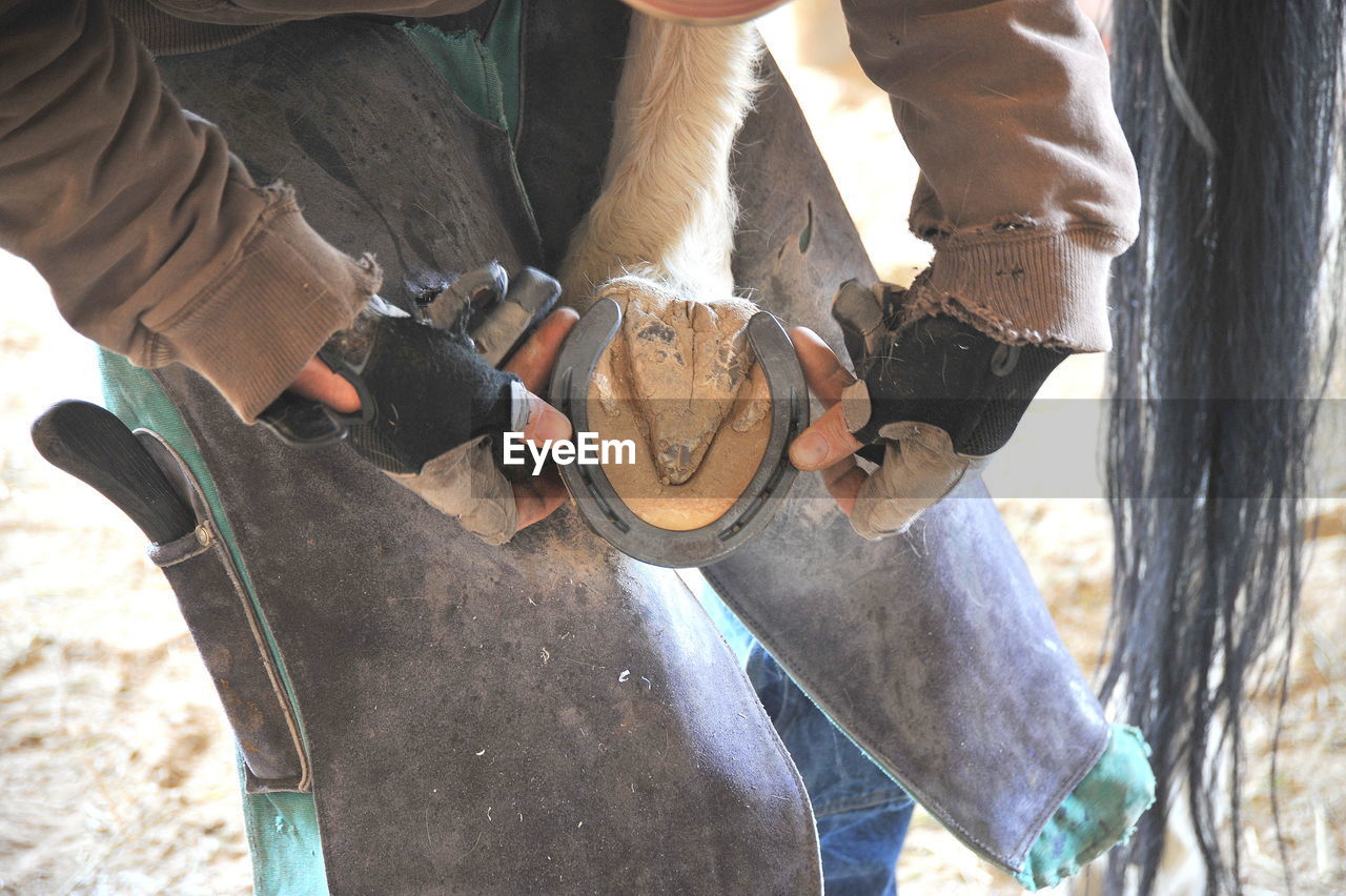 Midsection of men holding horse shoe