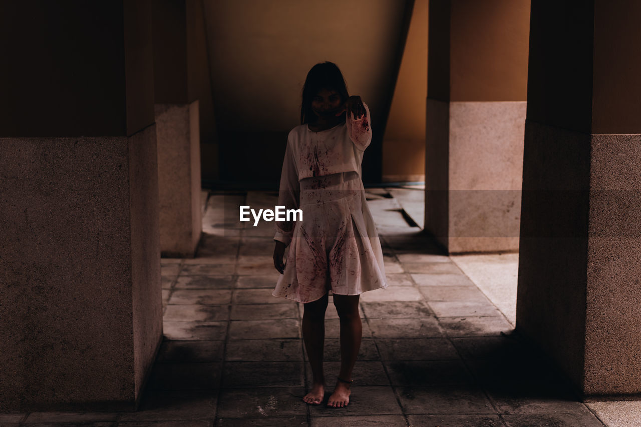 Full length of young woman with halloween make-up standing in corridor