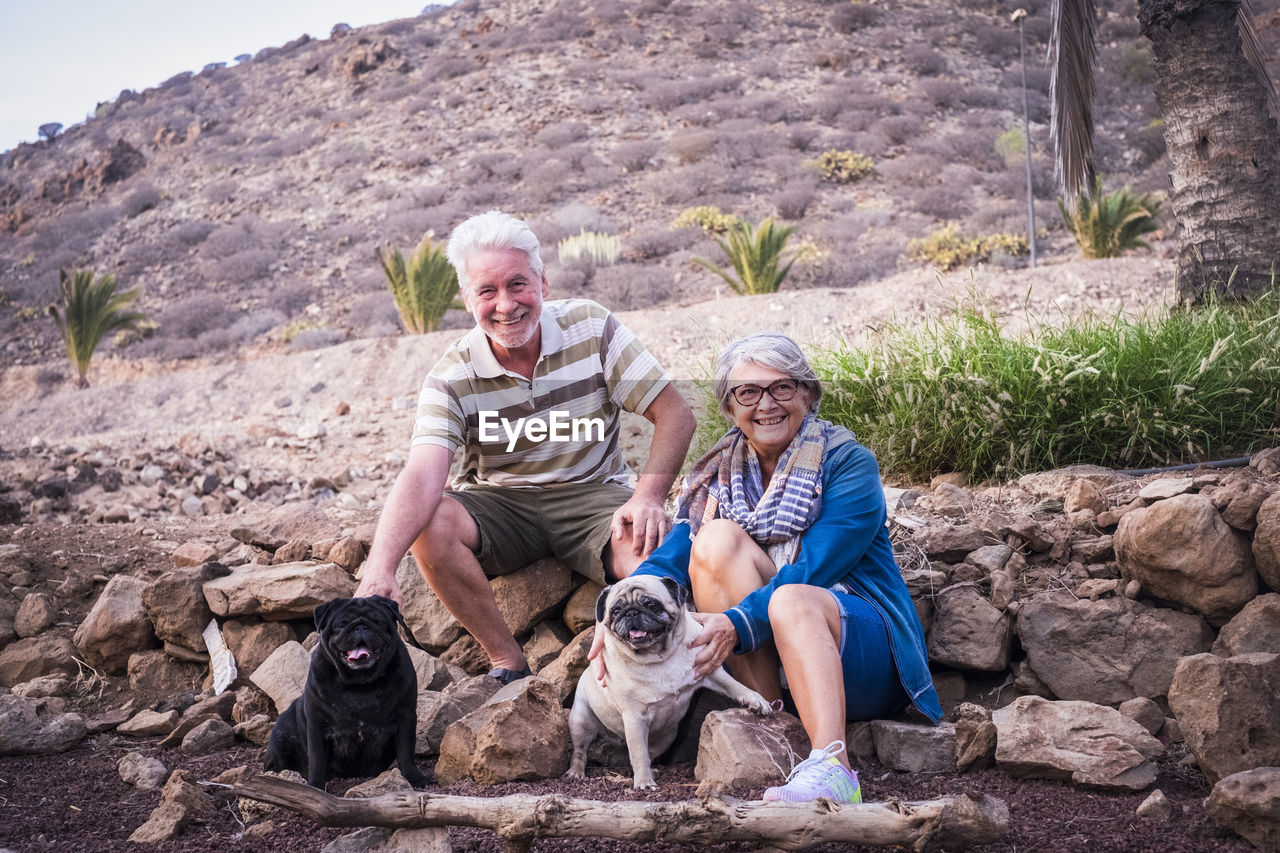 PORTRAIT OF FRIENDS WITH DOG SITTING ON STONE