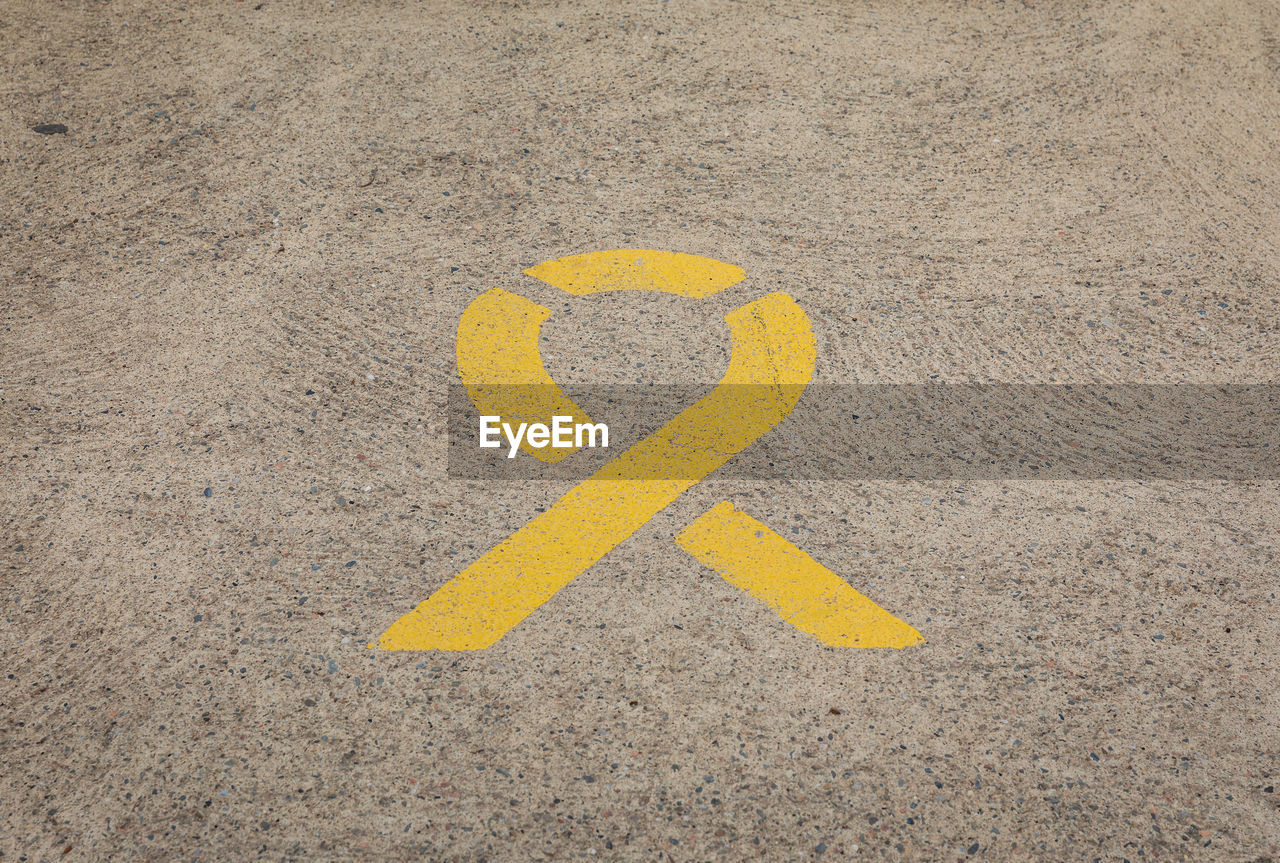 yellow, sign, sand, road, communication, no people, symbol, high angle view, day, transportation, circle, number, guidance, asphalt, line, outdoors, city, road marking