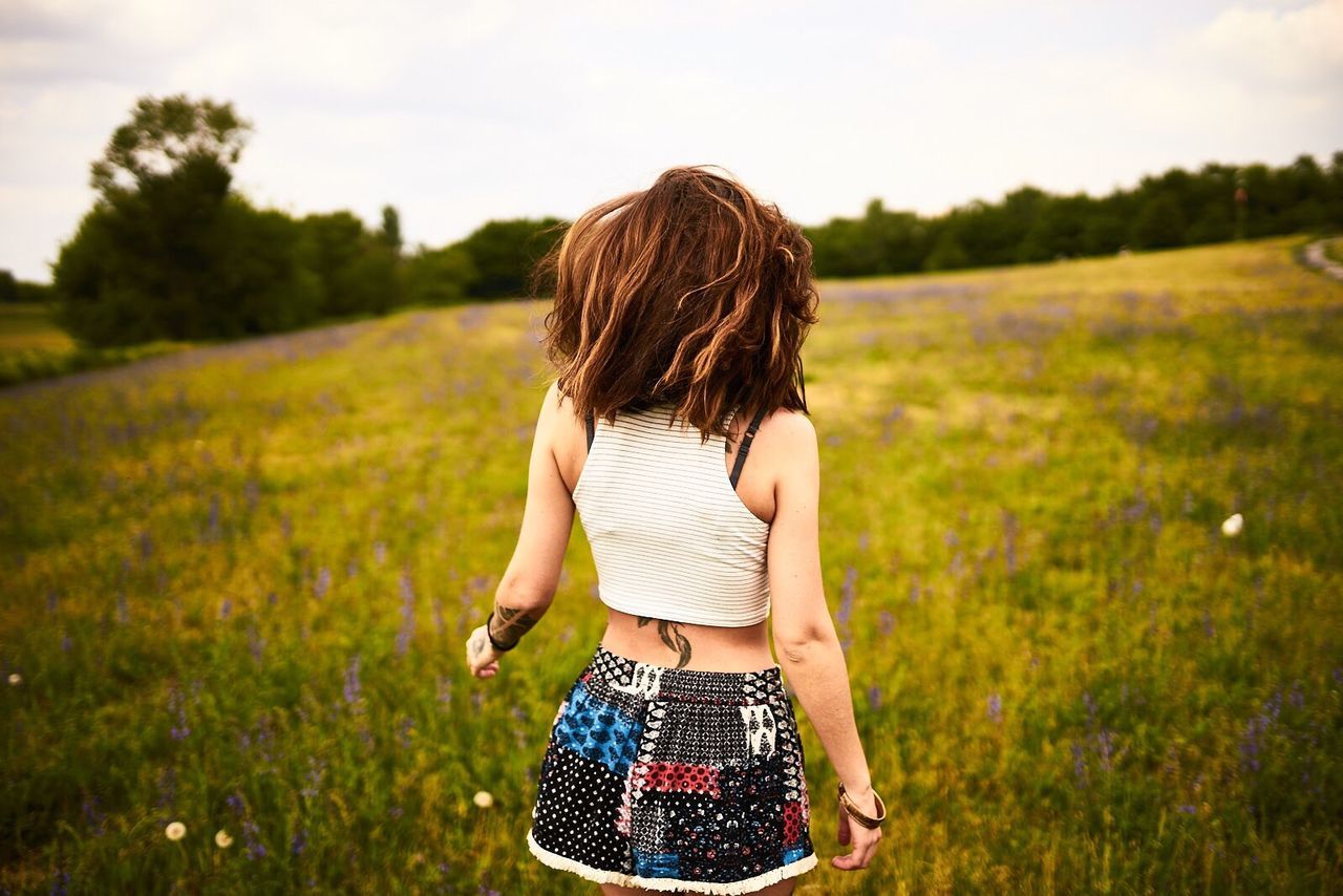 WOMAN STANDING ON GRASSY FIELD