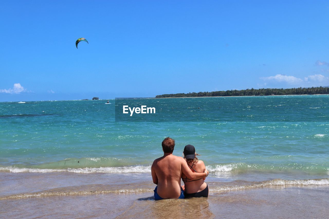 Rear view of couple sitting at beach