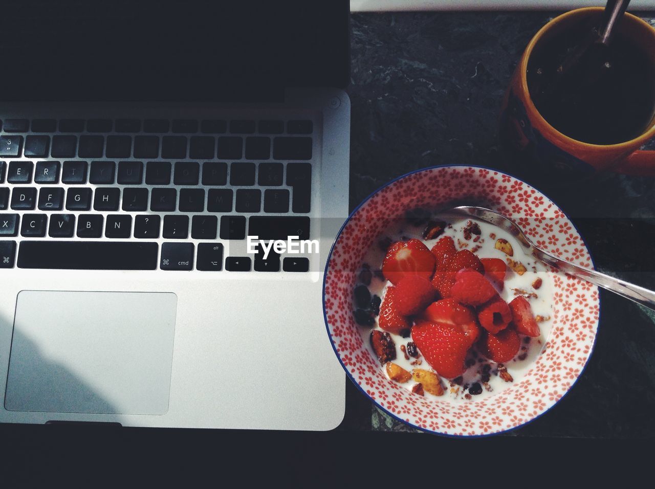 Granola with strawberries by laptop