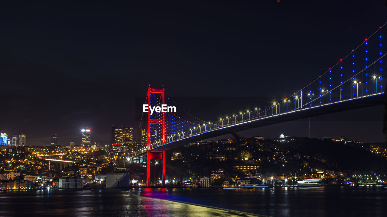 Illuminated bridge over river at night