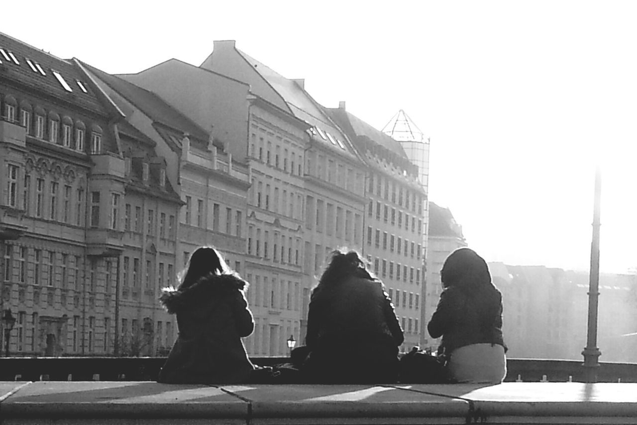 Rear view of women sitting against buildings in city