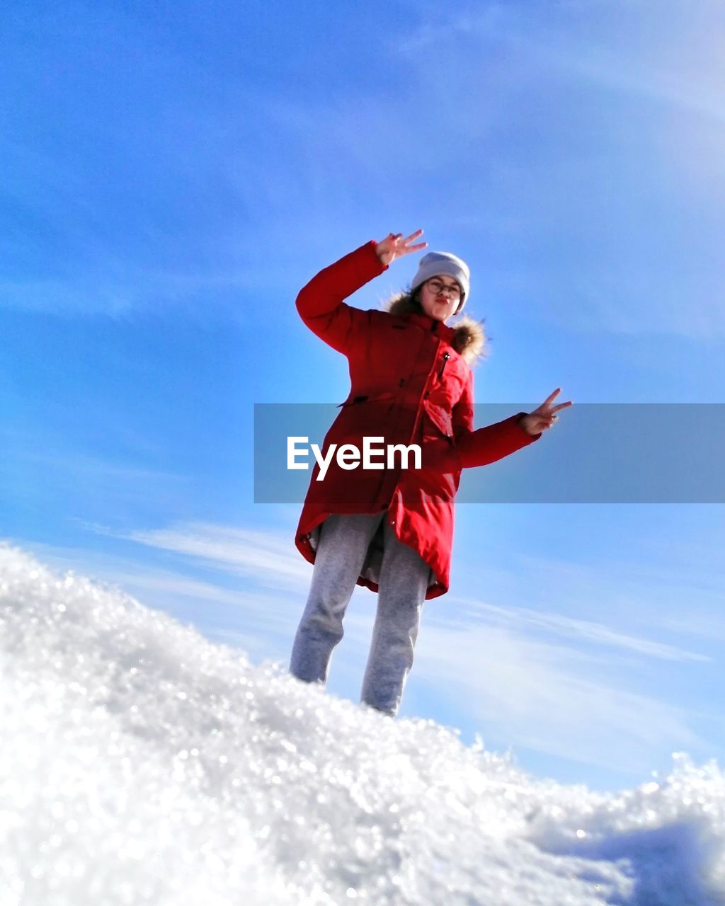 Low angle view of girl standing on snow against sky