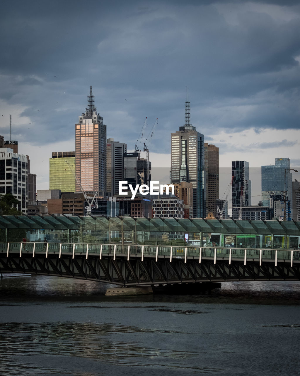 Modern buildings by river against sky in city