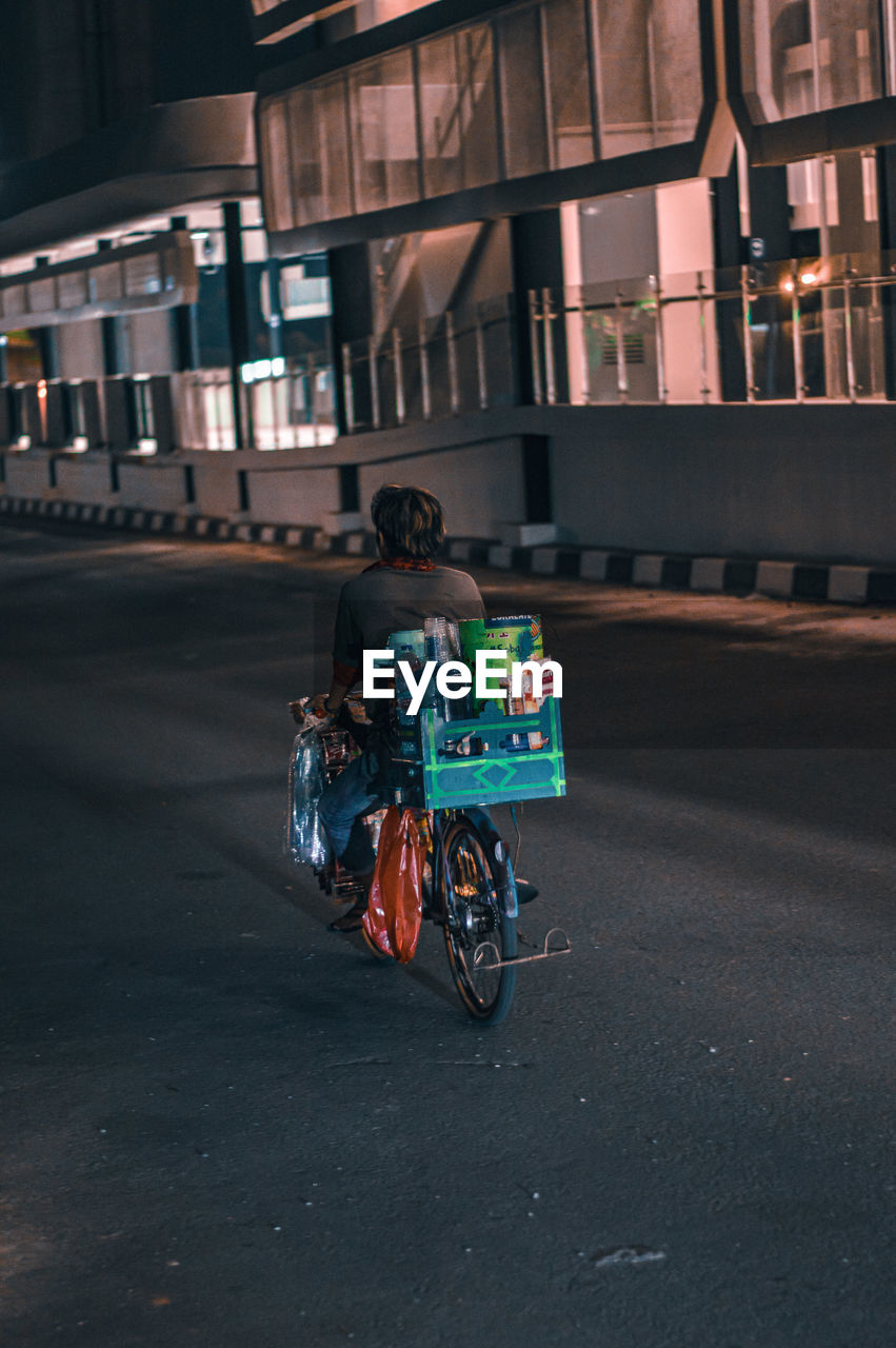 Back view of people riding bicycles on city street