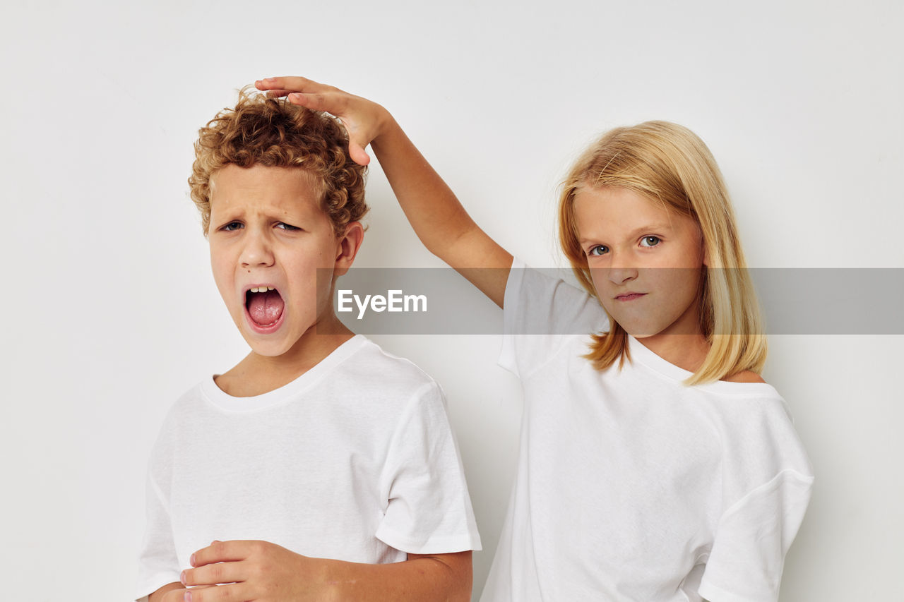 Portrait of sibling fighting against white background