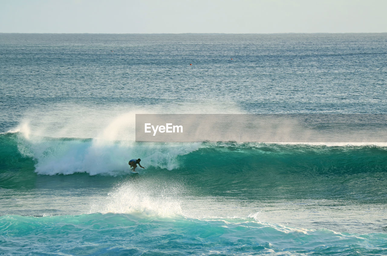 Distant view of man surfing in sea