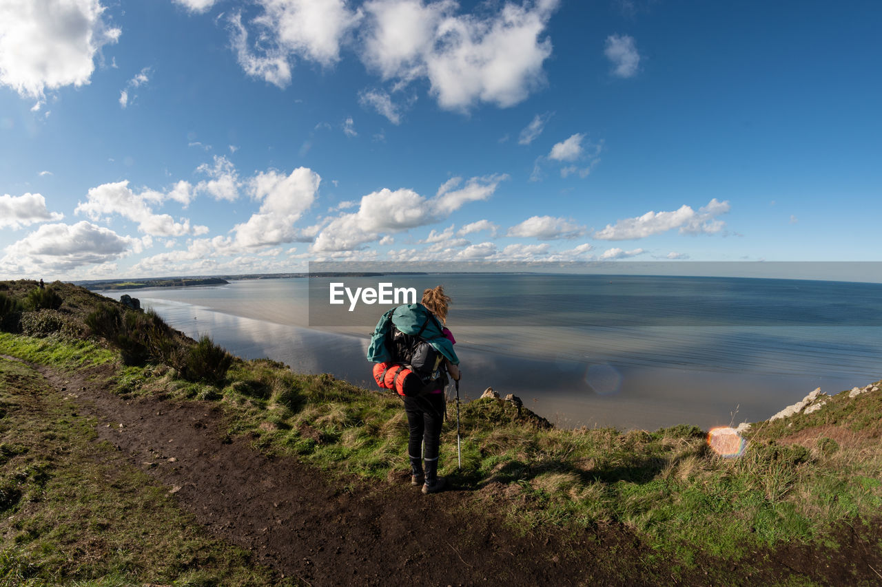 Rear view of women on shore against sky