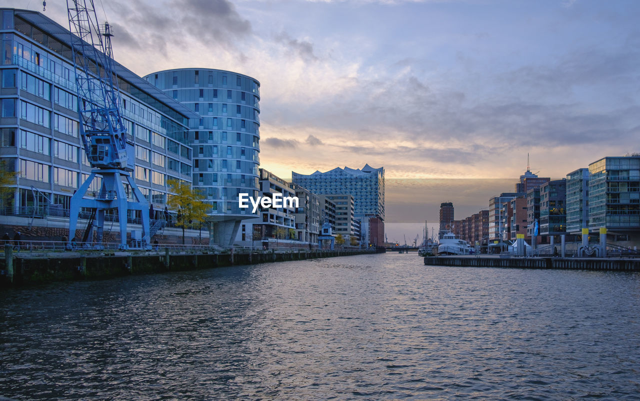 MODERN BUILDINGS BY RIVER AGAINST SKY