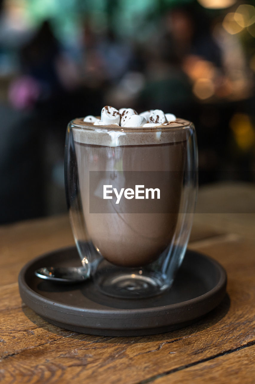 CLOSE-UP OF COFFEE CUP ON GLASS TABLE