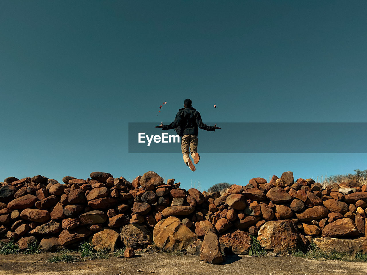 Young man levitating over rock wall