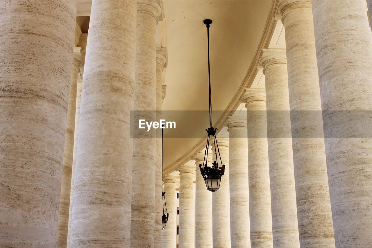 Low angle view of lamp hanging amidst st peters square columns
