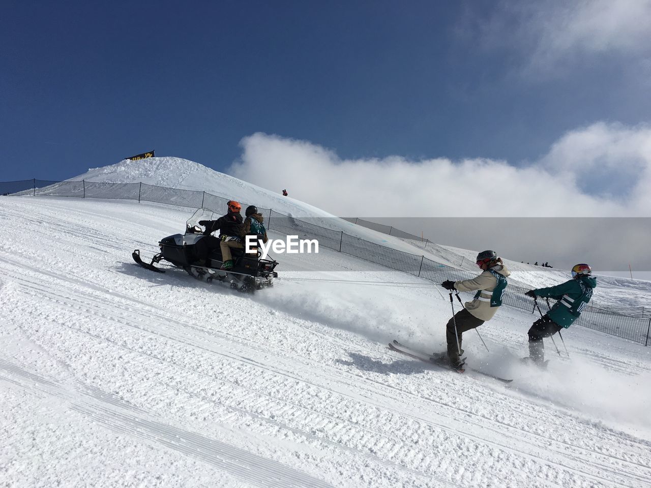 People snowmobiling and skiing on mountain