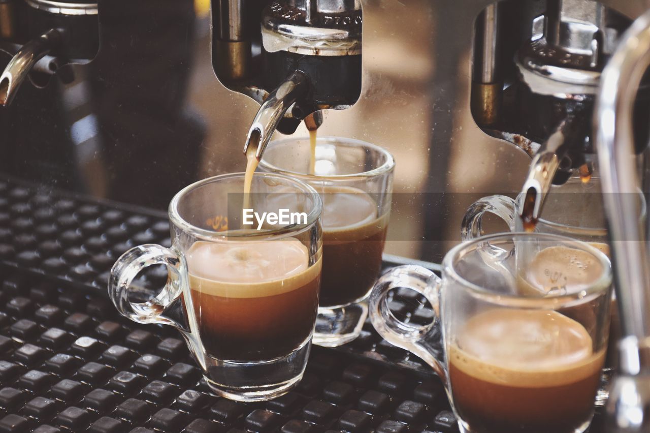 Coffee pouring from machine in cups