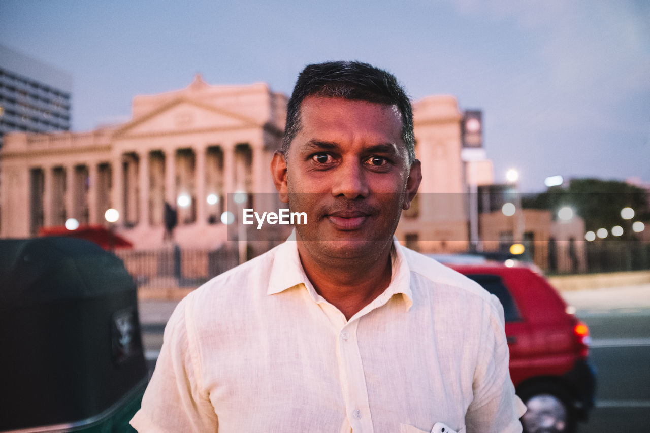 PORTRAIT OF MATURE MAN IN CITY AGAINST SKY