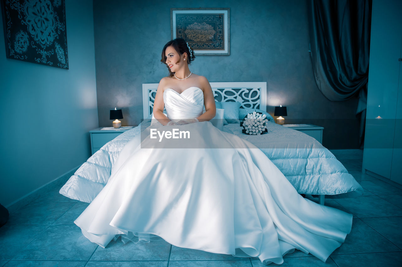 Bride sitting on bed at home