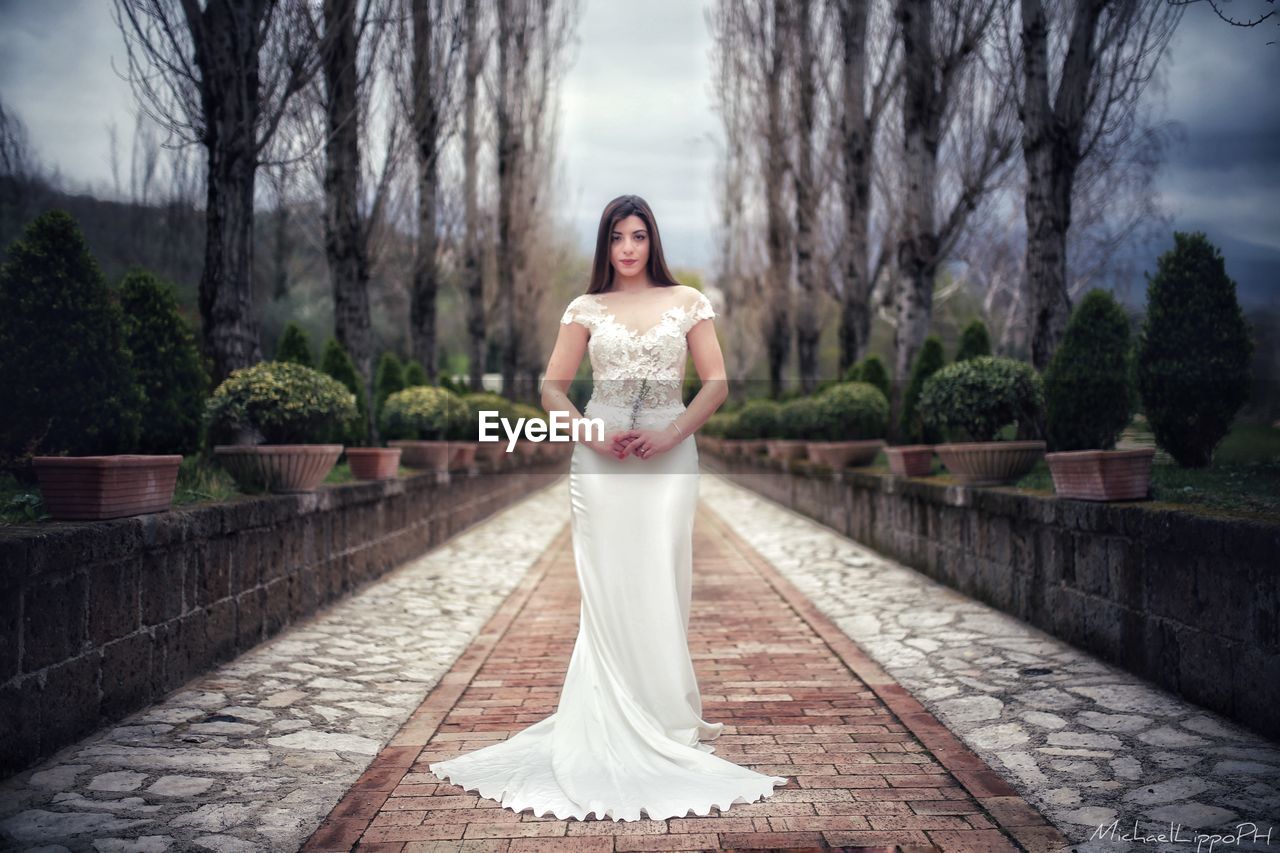 PORTRAIT OF WOMAN STANDING BY TREES