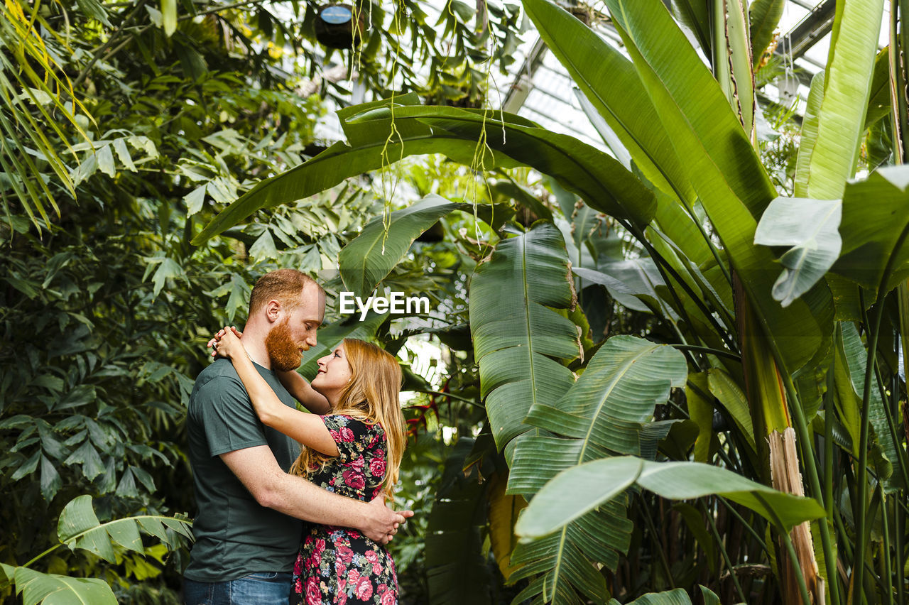 Redhead heterosexual couple embracing each other while standing in park