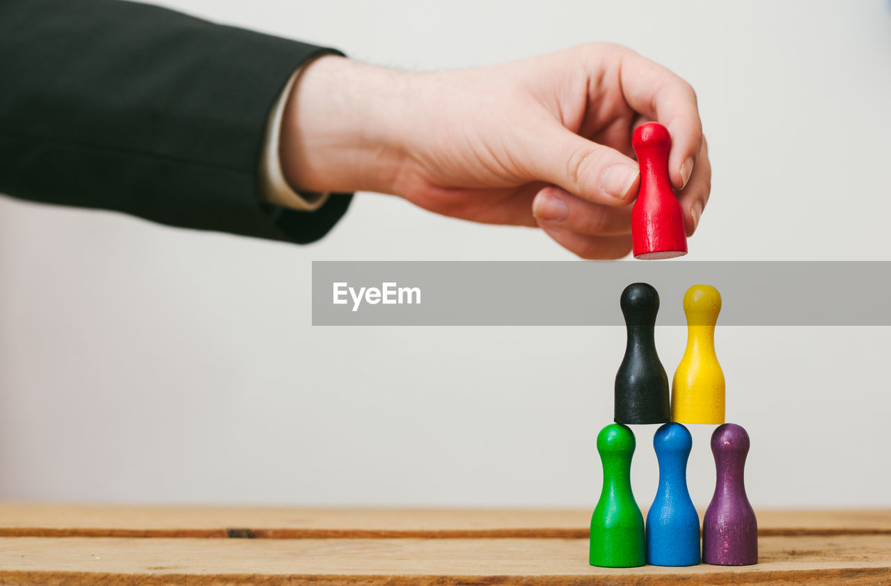 Cropped hands holding colorful toys over wooden table