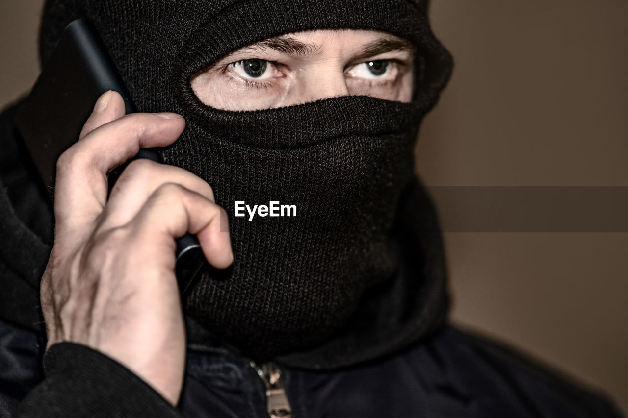 black, portrait, one person, clothing, adult, headshot, hiding, facial hair, human face, men, looking at camera, covering, young adult, human head, glasses, cap, hat, studio shot, security, indoors, disguise, hood, obscured face, human eye, hand, emotion, hood - clothing, protection, aggression, eye, front view, person, close-up, social issues, human hair, dark