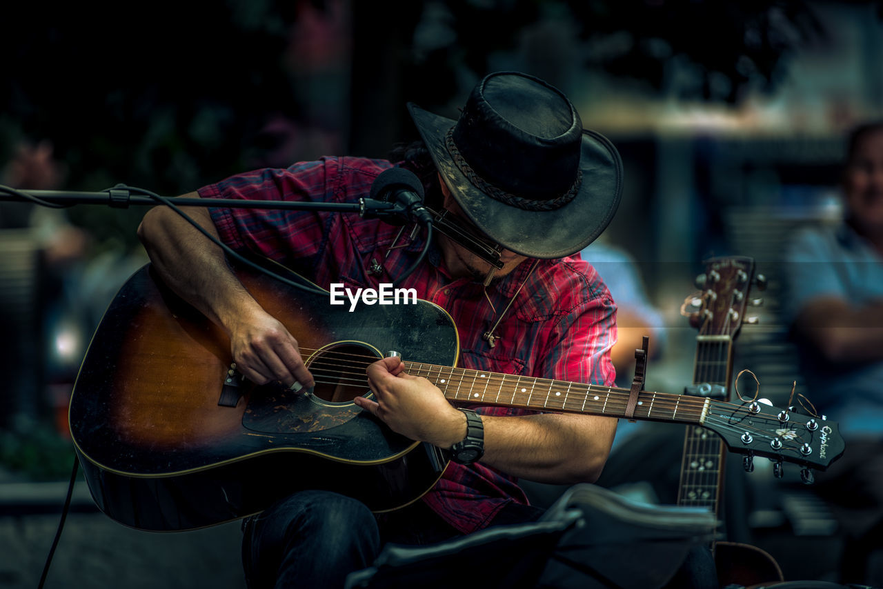 MIDSECTION OF MAN PLAYING GUITAR AT CAMERA