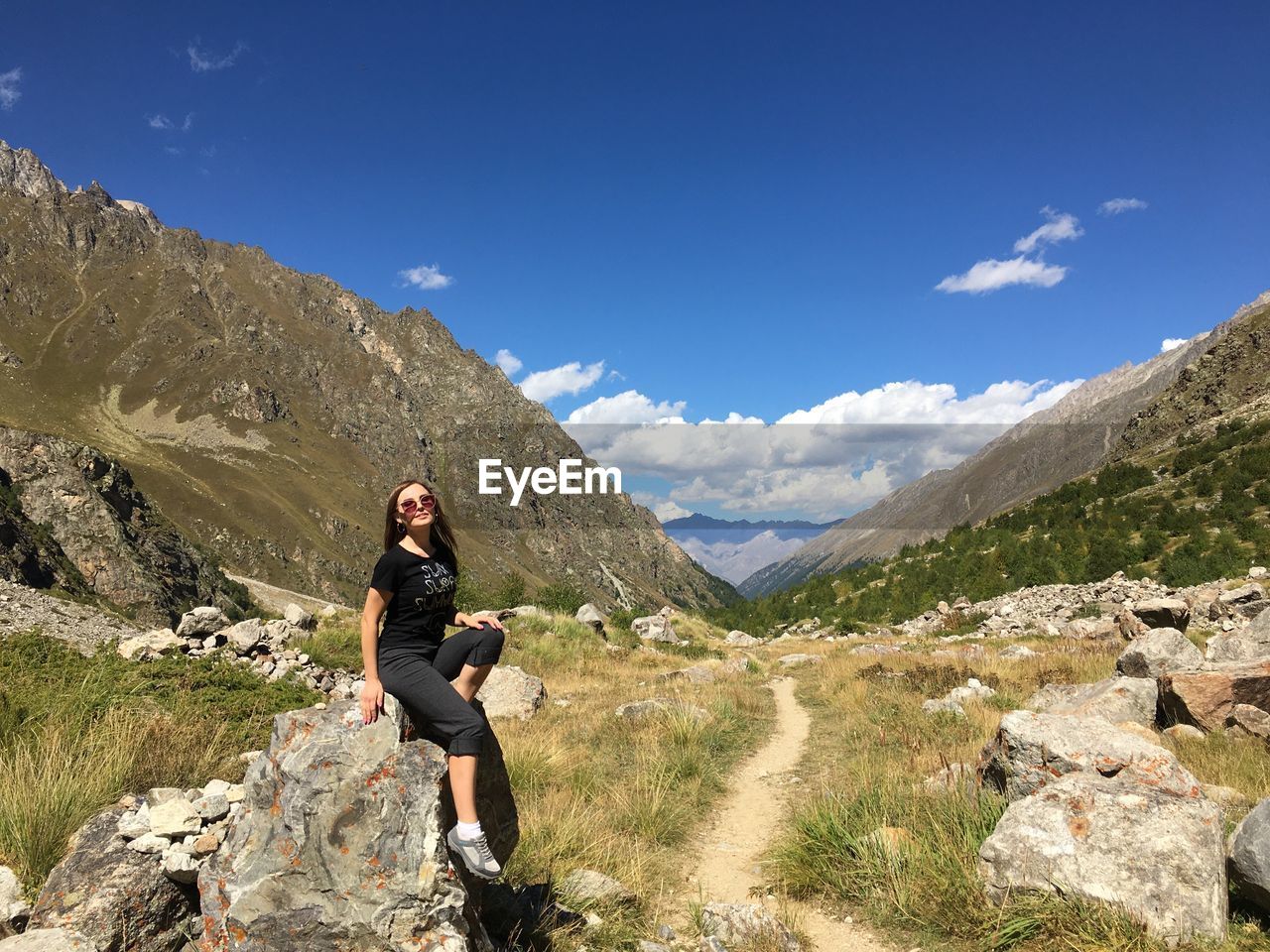 MAN STANDING ON ROCKS AGAINST MOUNTAINS