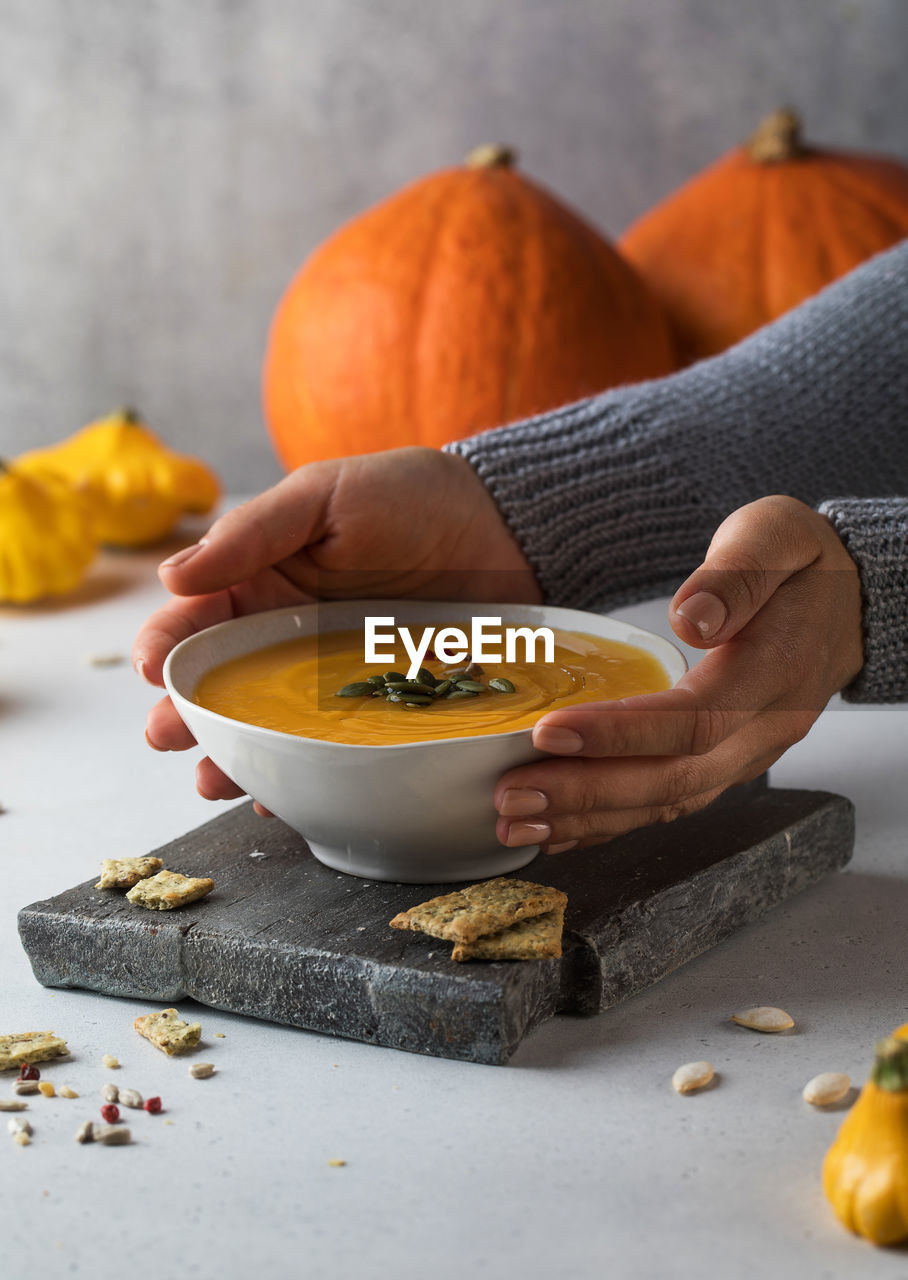 A bowl of warm pumpkin soup with seeds in your hands. comfortable riding. vegetarian dishes.