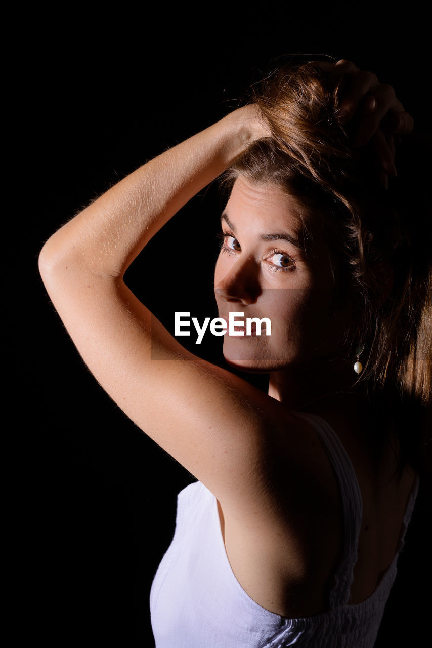 Close-up portrait of mid adult woman against black background