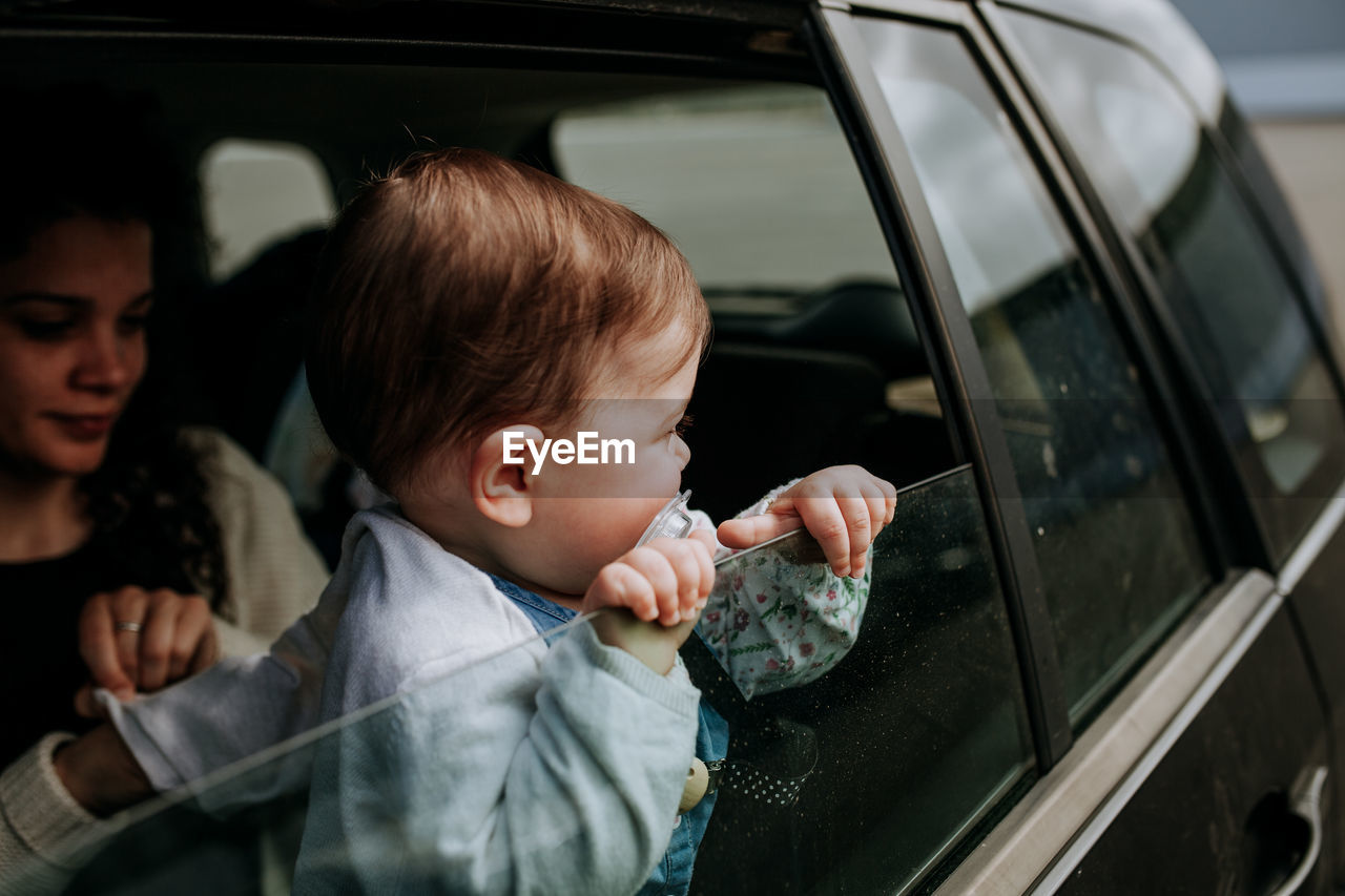 Toddler with mother looking through car window