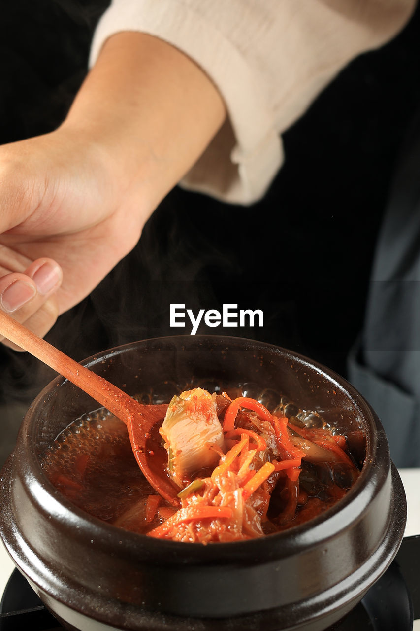 Female hand cooking kimchi stew soup or kimchi jigae, korean traditional food 