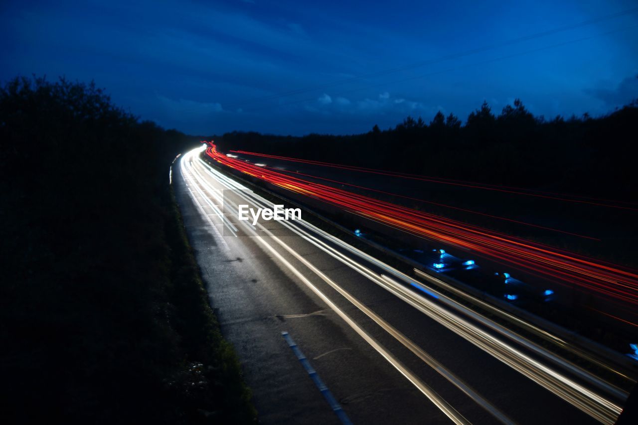 Light trails on highway against sky
