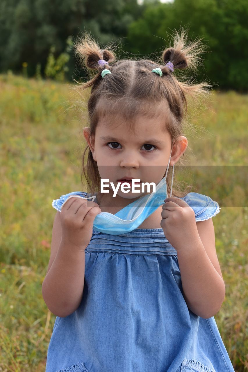 Portrait of cute girl holding camera on field