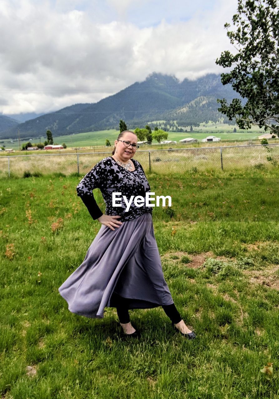 Portrait of woman walking on field against sky