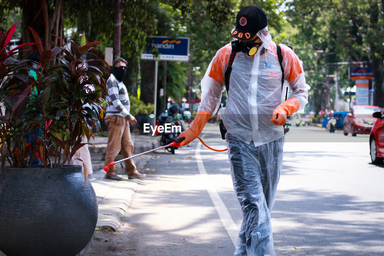 REAR VIEW OF PEOPLE WALKING ON ROAD