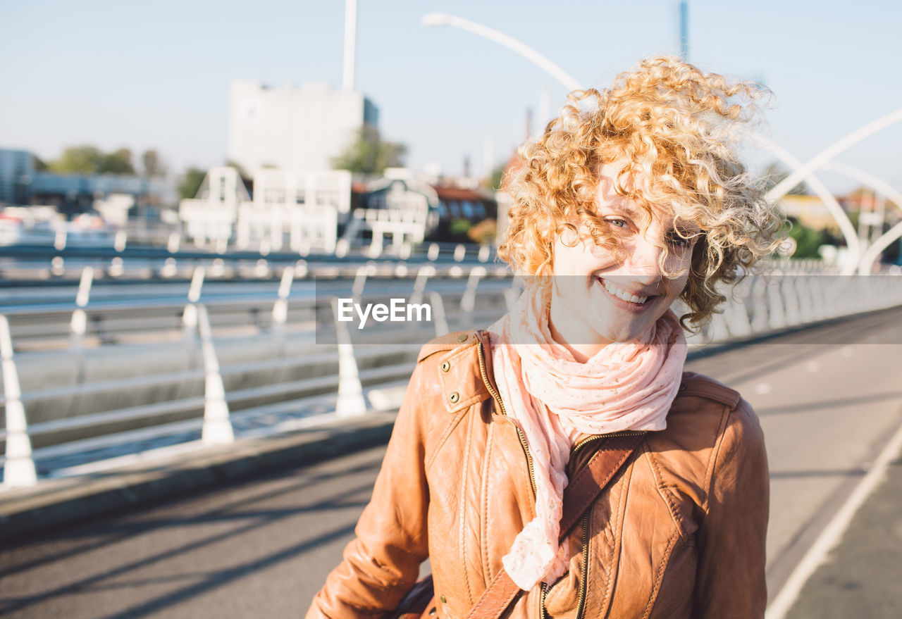 Portrait of smiling woman standing against sky