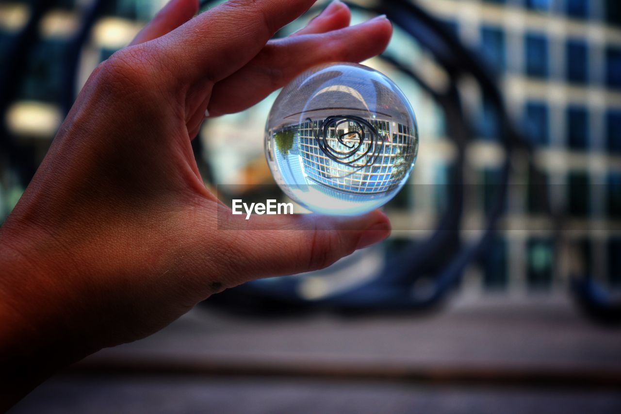 Low angle view of hand holding crystal ball