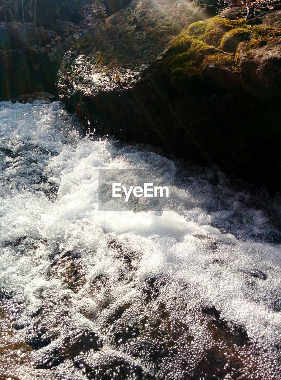 High angle view of stream flowing by rock