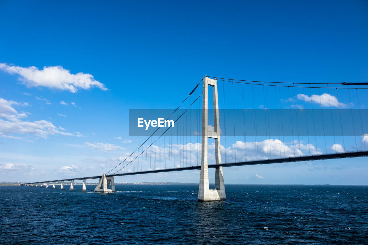 Suspension bridge over sea against clear blue sky