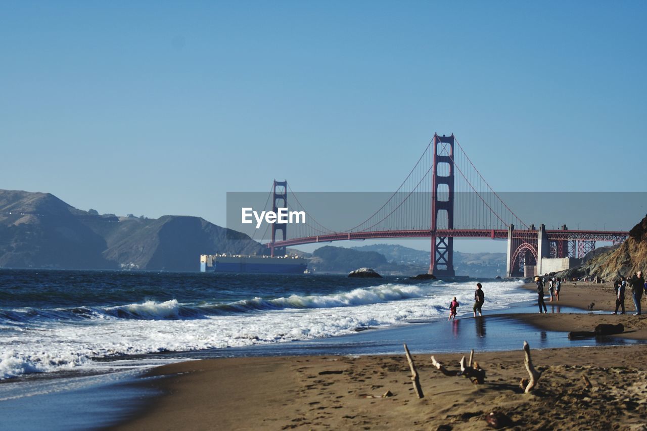 VIEW OF SUSPENSION BRIDGE AT BEACH AGAINST CLEAR SKY