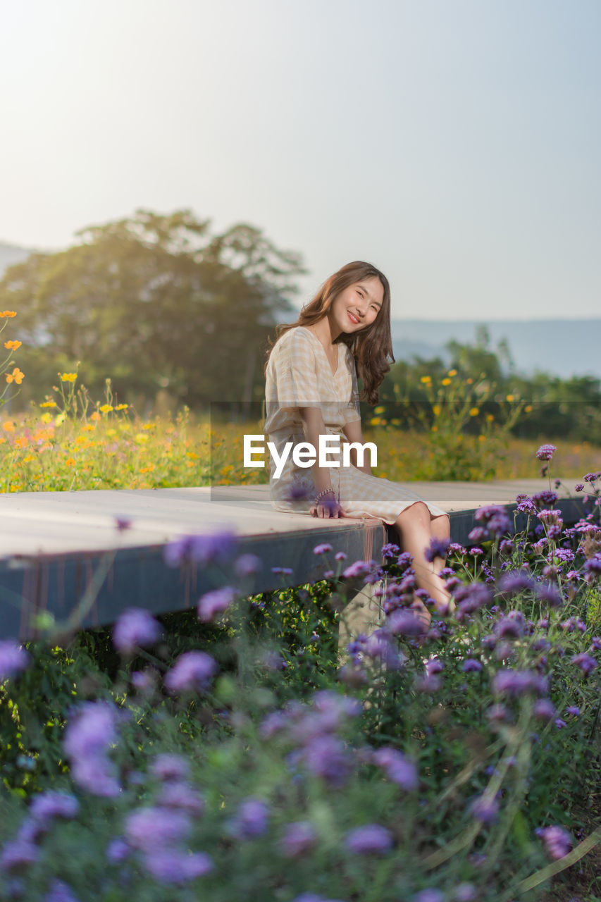 Woman standing by purple flowering plants